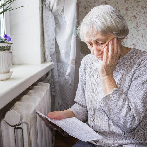 An older lady looking worriedly at her gas bill