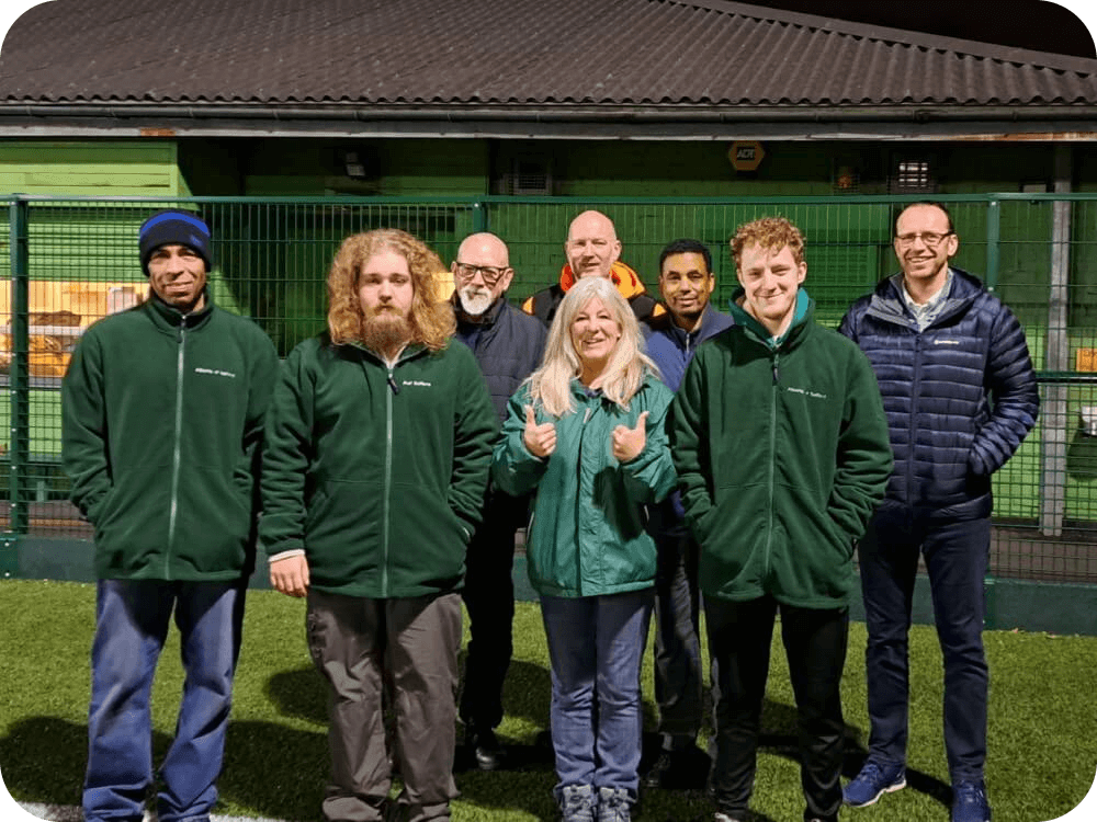A group of people from ALberts of Salford, stood on a football pitch