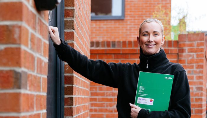 A young woman from Salix Homes knocking on the front door of a house