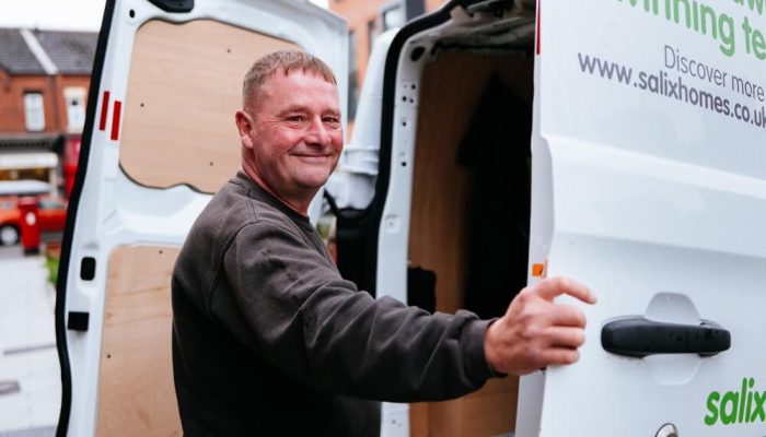 A smiling workman, opening the doors of a Salix Homes van