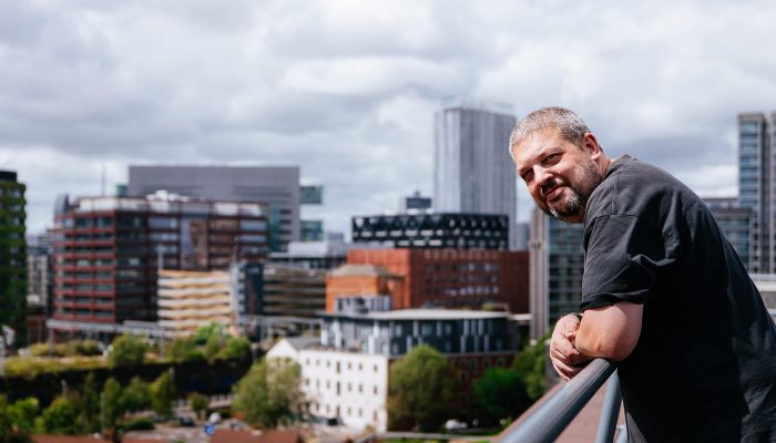 A workman standing on the roof of a building, overlooking a city skyline