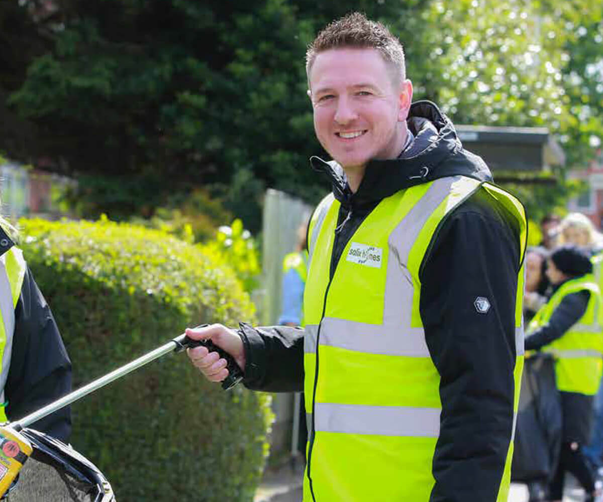 A man in a Salix Homes uniform, litter picking